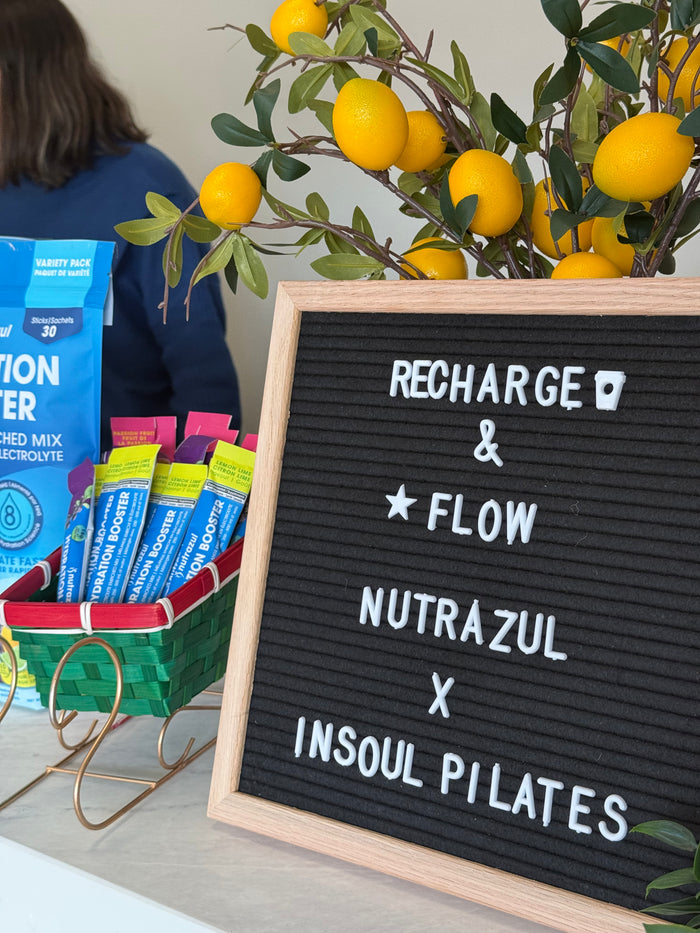 A letter board reading Recharge and Flow, Nutrazul x Insoul Pilates, beside Hydration Booster sticks
